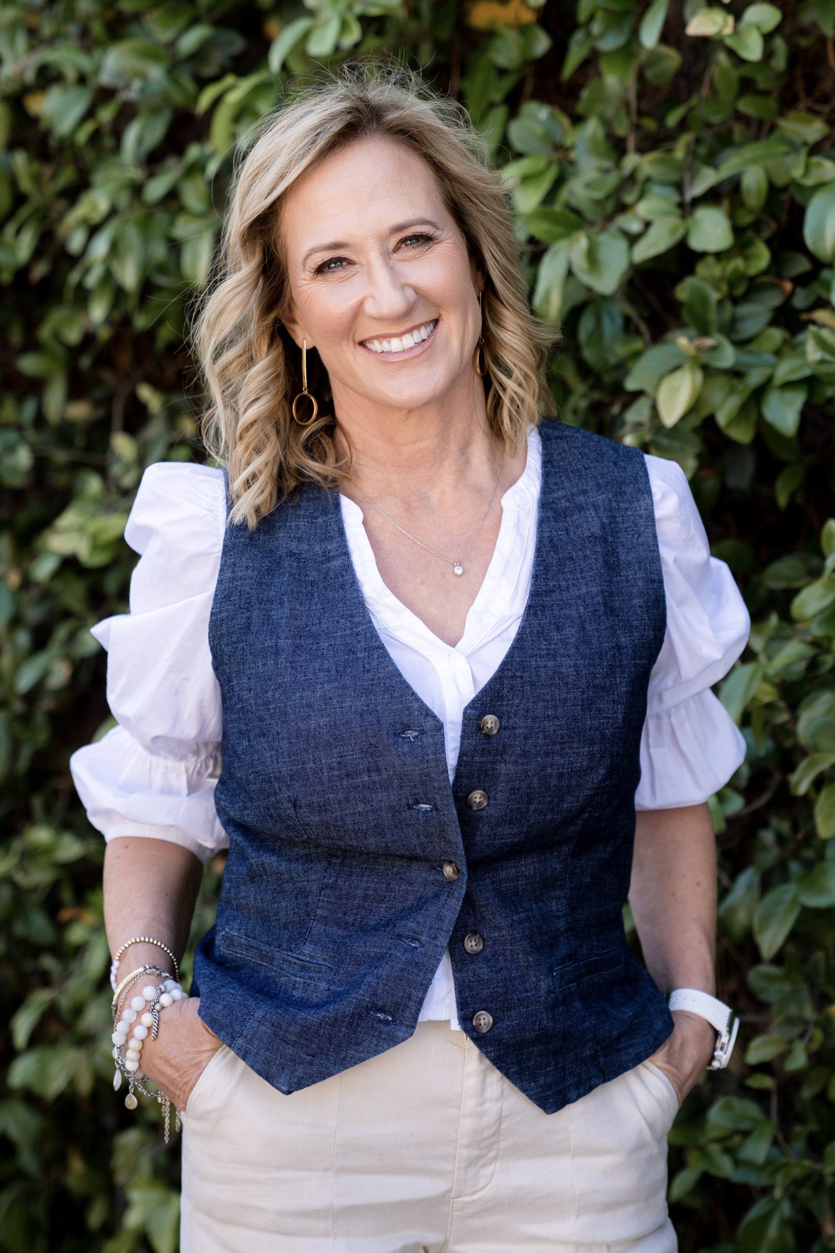 Carlyn Bushman smiling in front of green background wearing vest – featured partner of Revenue Growth Advisors